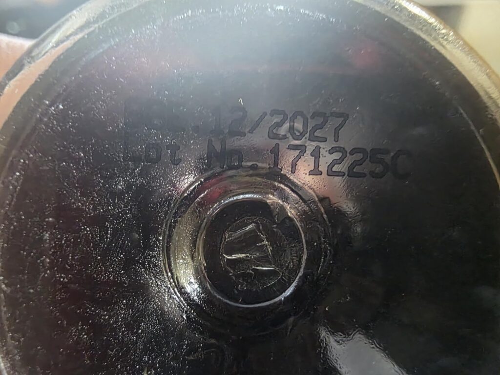 Gros plan sur le dessous du flacon, avec la date d'expiration et le numéro de lot.
