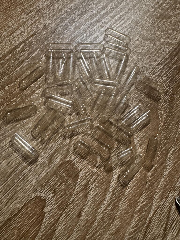 Un tas de gélules vides transparentes sur une table en bois.