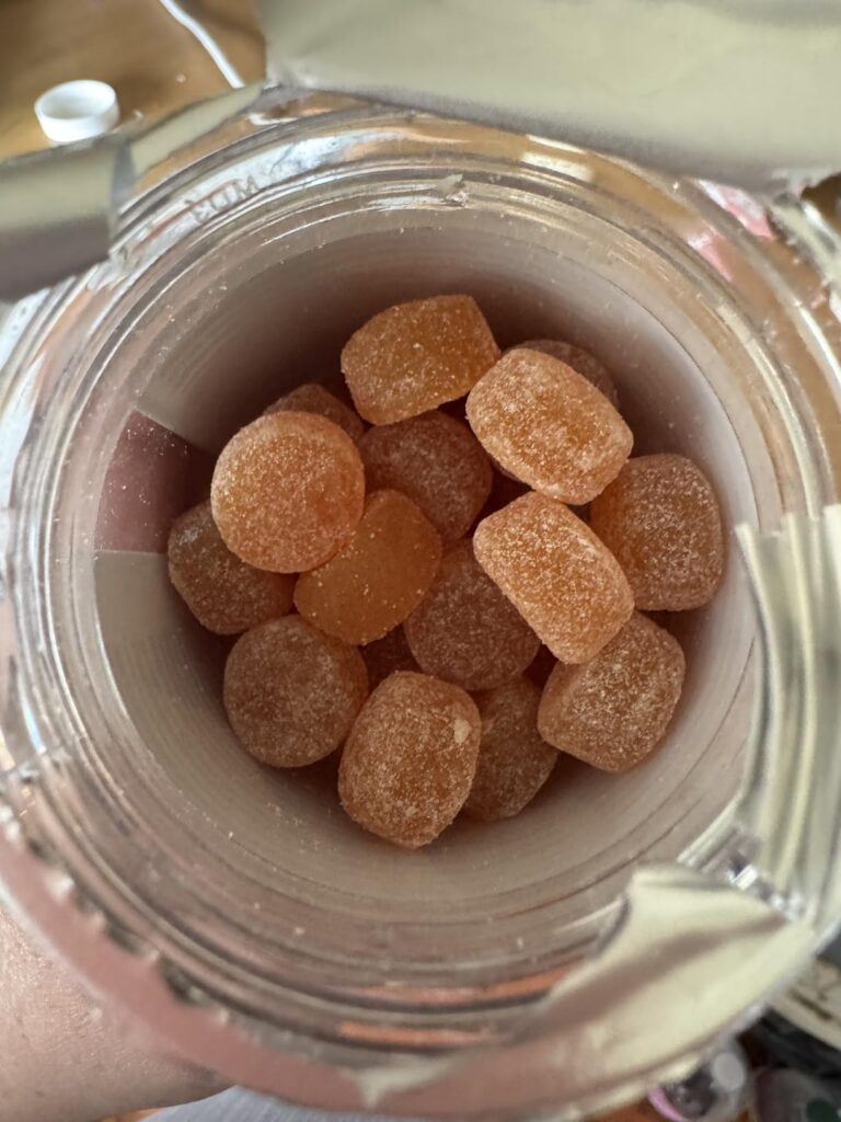 Vue de l'intérieur d'un pot transparent rempli de bonbons gélifiés orange.