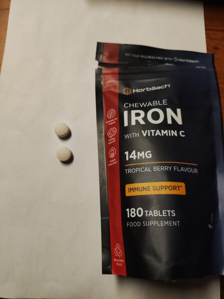 Sachet du produit posé sur une feuille blanche, avec deux comprimés extraits du sachet.