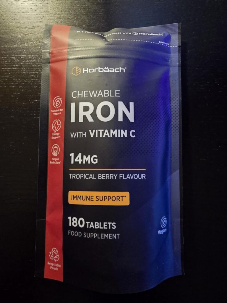 Sachet du produit fermé, posé sur un plan de travail sombre. Similaire au visuel 0 mais sans les comprimés et le sachet est f...