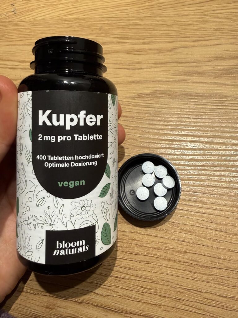 Bouteille de compléments alimentaires ouverte, couvercle à côté, montrant des pilules.