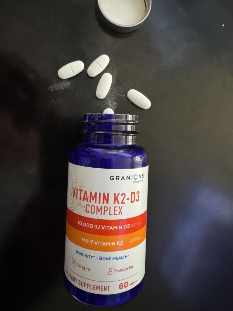 Flacon de vitamines K2-D3 ouvert avec des capsules blanches dispersées