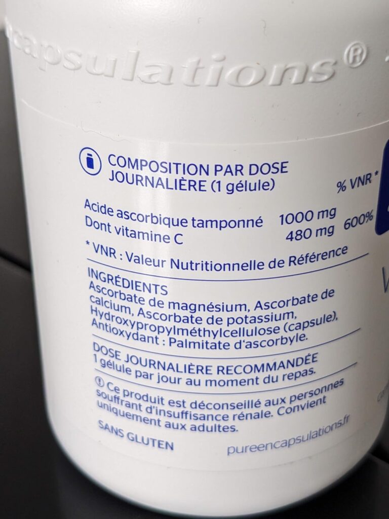 Gros plan sur l'étiquette arrière de la bouteille de Vitamine C, montrant la composition et les ingrédients.