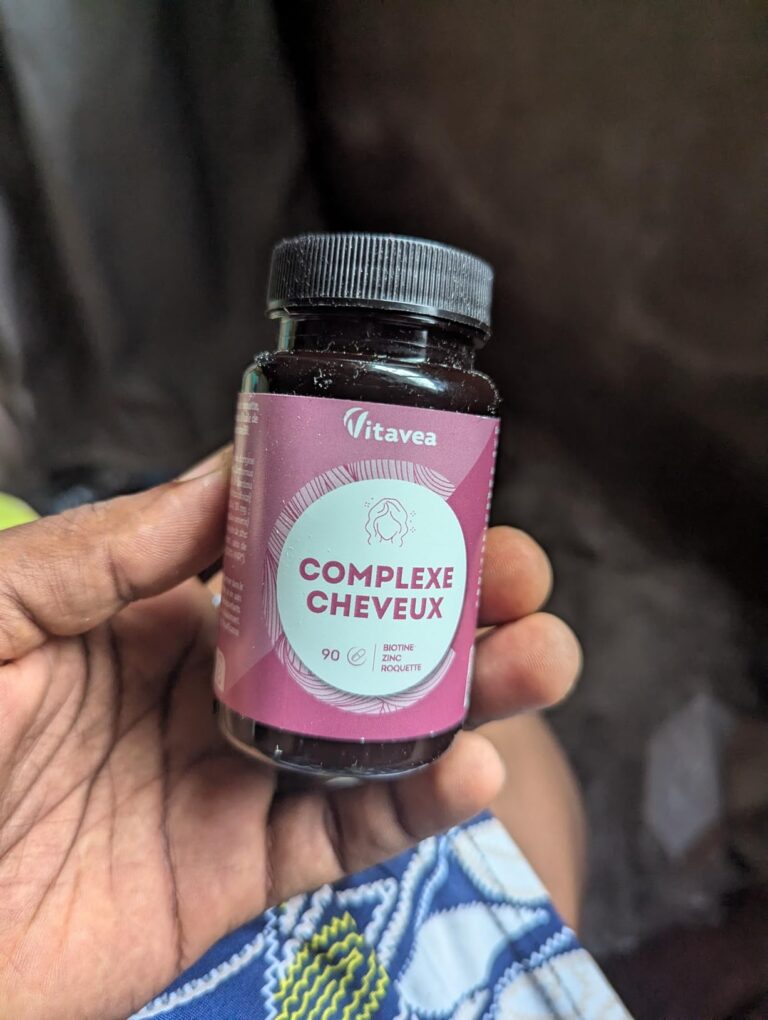Bouteille du produit tenue à la main, sur fond flou. Montre le même produit que les images 1 et 2.