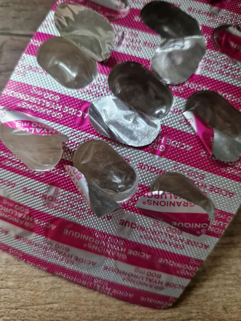 Blister de pilules vide, montrant la surface rose et le texte imprimé.