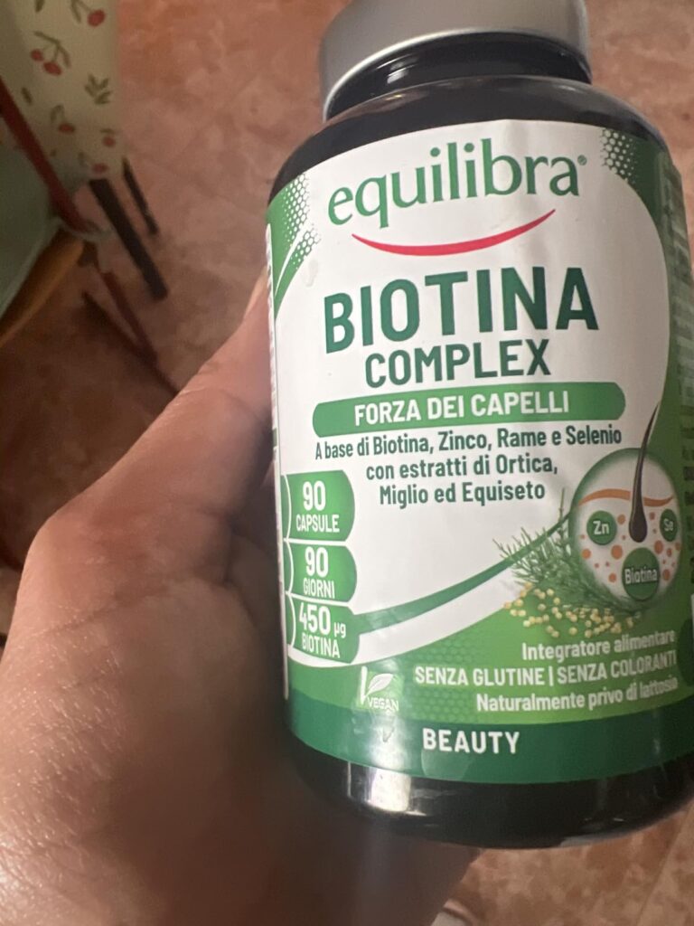 Flacon de compléments alimentaires Biotine Complex tenu dans une main, vue de face.