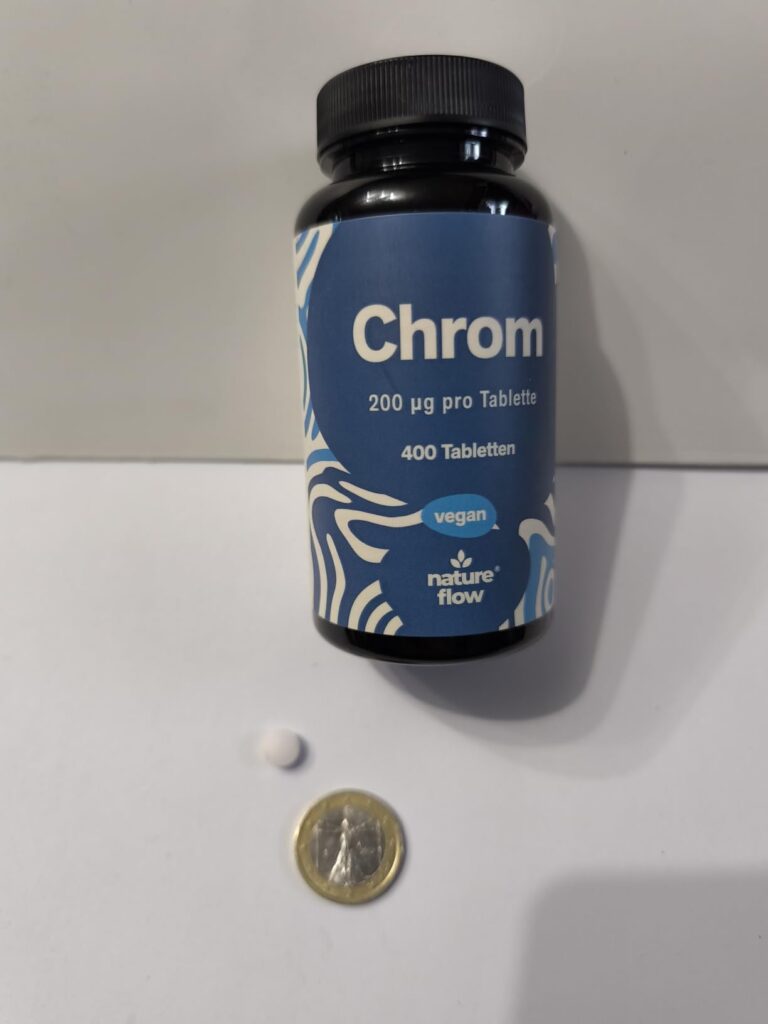 Flacon de comprimés de chrome et un comprimé posés à côté d'une pièce de 1 euro.