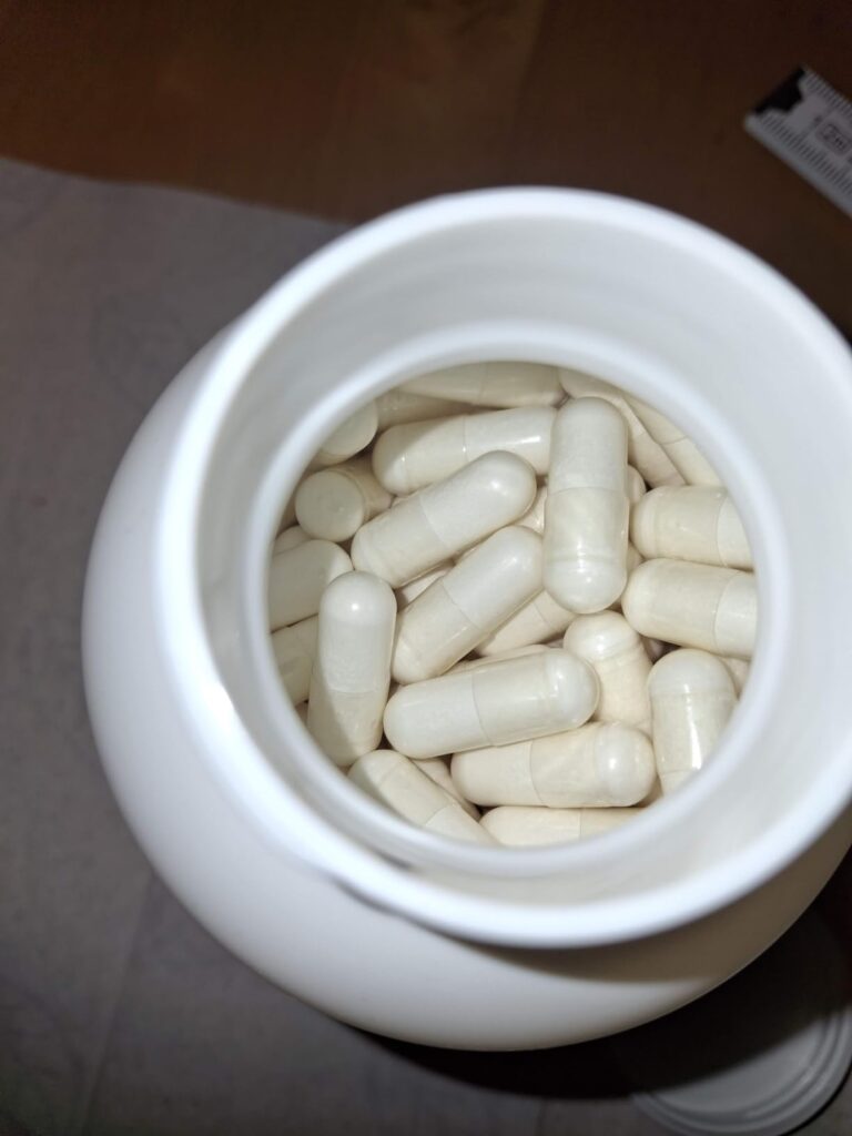 Vue en plongée d'une bouteille en plastique blanc remplie de gélules.