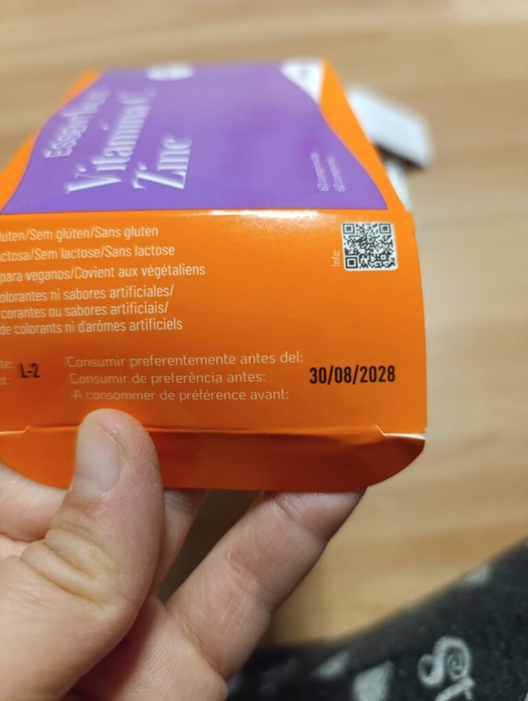 Gros plan sur un côté de la boîte d'emballage du produit. Il est tenu par une main, sur un fond en bois.