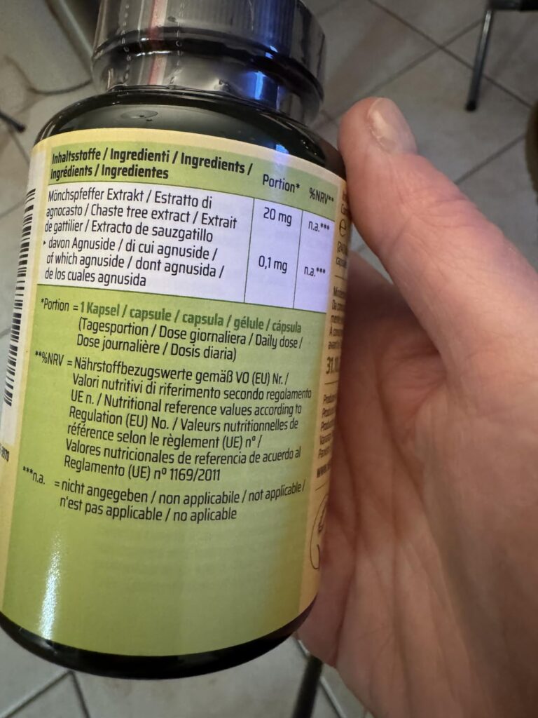 Bouteille de compléments alimentaires Vitex Agnus Castus tenue dans une main, vue de côté. L'étiquette présente les ingrédien...