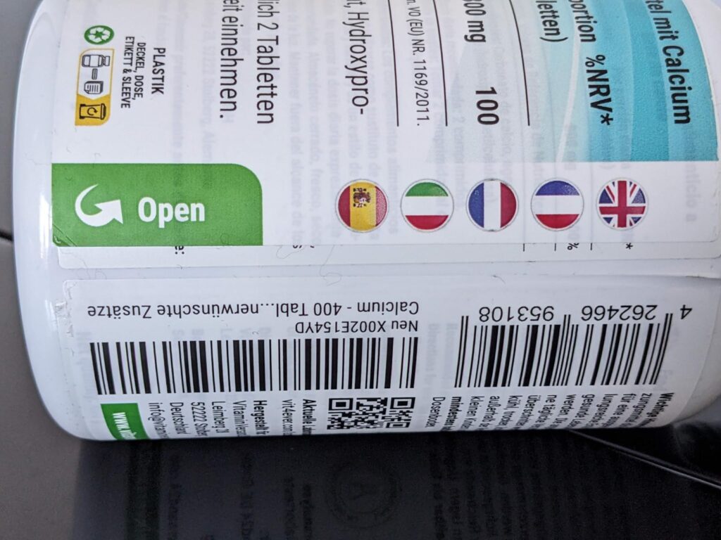 Détail de la partie inférieure de l'étiquette du produit, montrant un code-barres, un QR code et des drapeaux de pays. C'est...