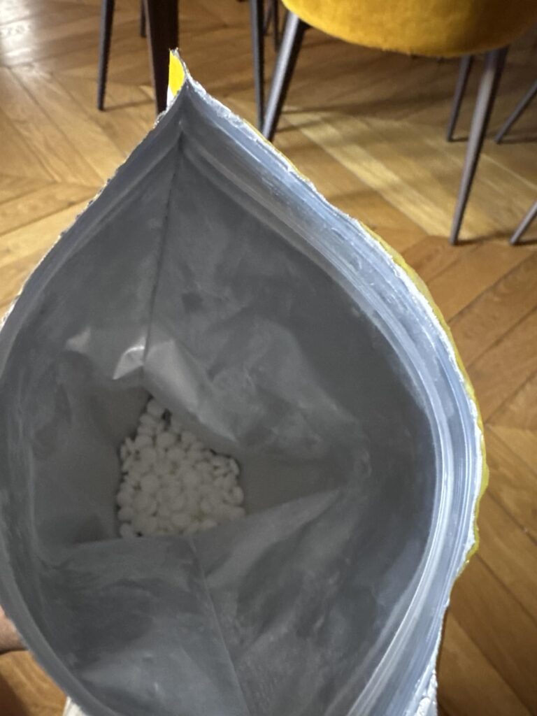 Vue de l'intérieur du sachet ouvert, avec les comprimés blancs visibles au fond. L'image est prise d'un angle plongeant, mont...