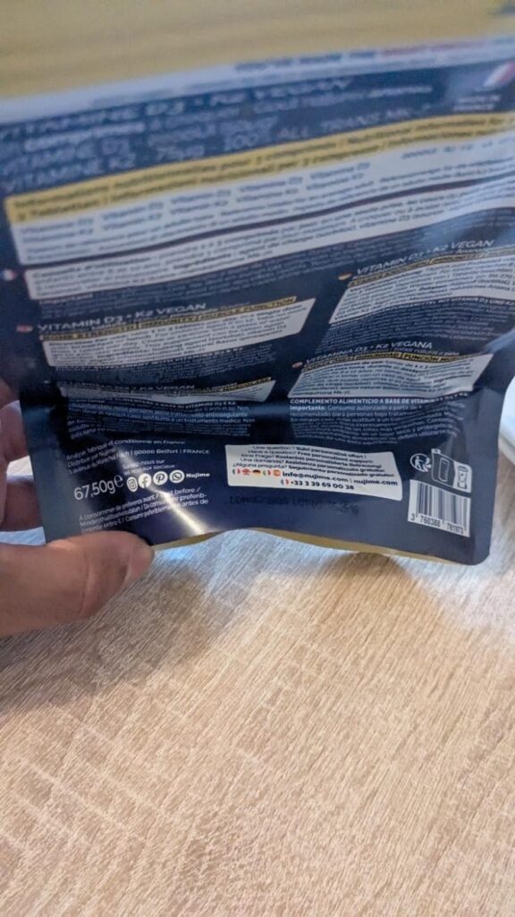 Gros plan sur le bas du dos du sachet de vitamines, montrant les informations nutritionnelles et codes-barres. Le sachet est...