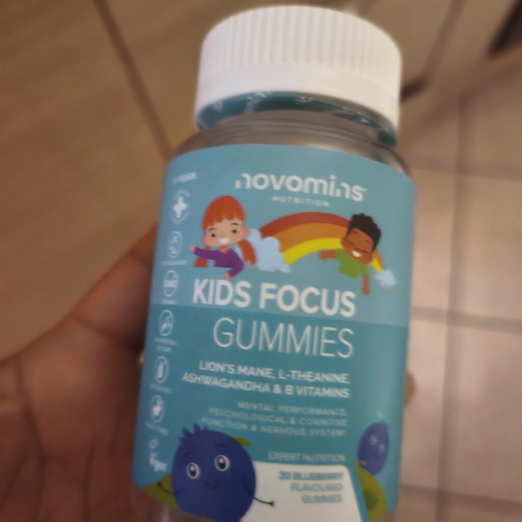 Gros plan sur l'étiquette du flacon de Novomins Kids Focus Gummies tenu par une main.