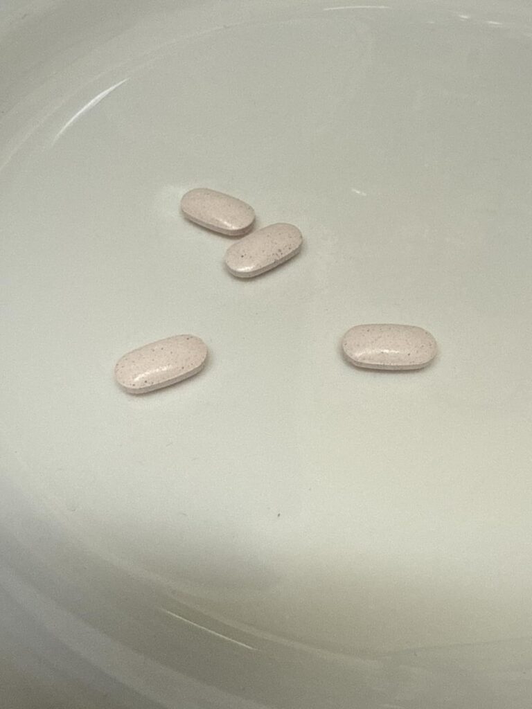 Quatre comprimés de vitamine B12 sur une surface blanche.