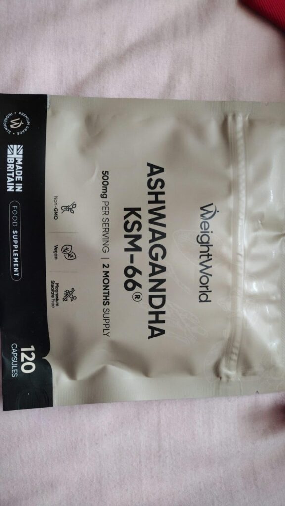 Vue en plongée du paquet de compléments WeightWorld Ashwagandha KSM-66. Le paquet est gris avec un bandeau noir en bas. On li...