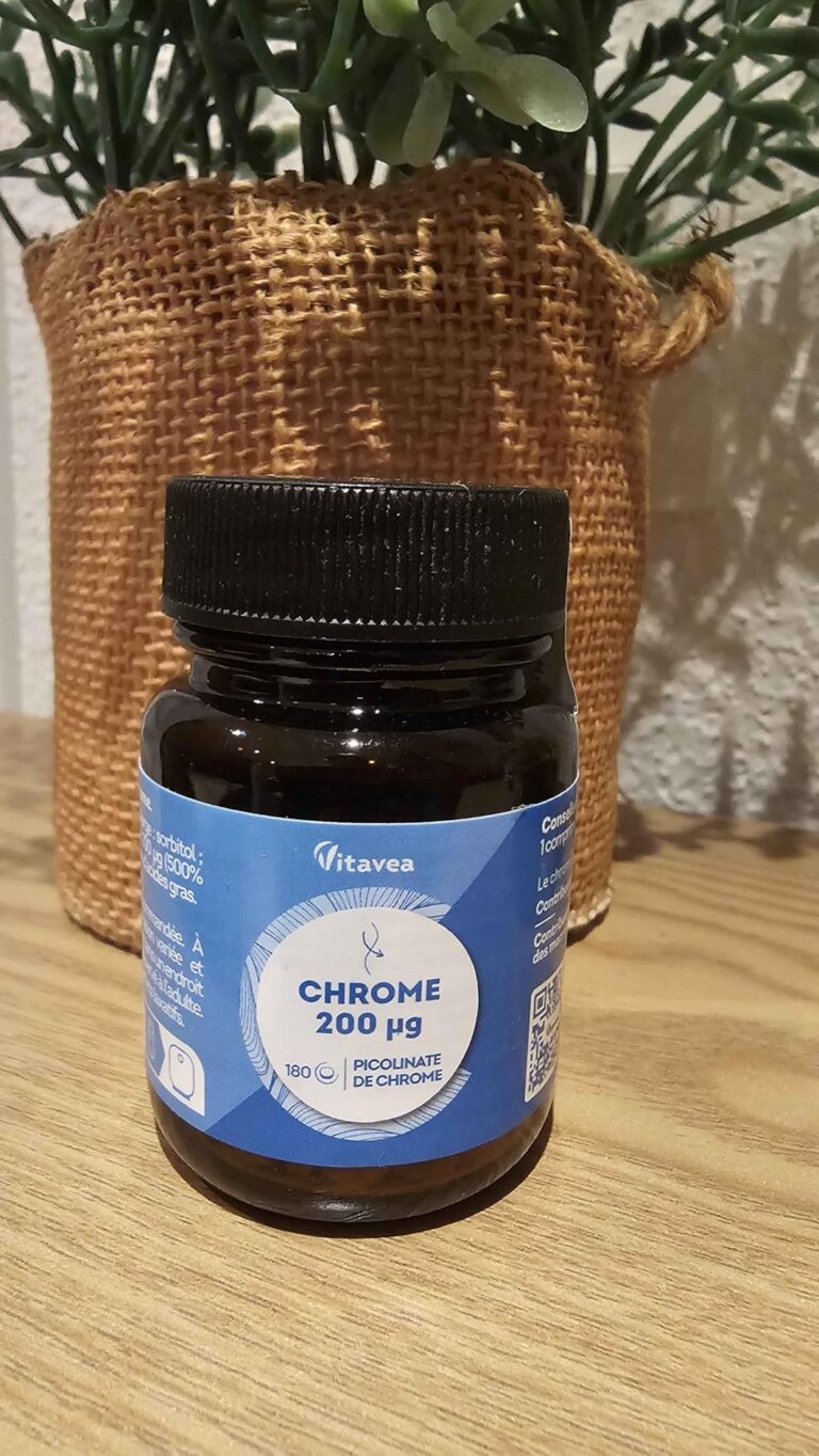 Flacon de chrome Vitavea posé sur une table en bois, devant une plante en pot.