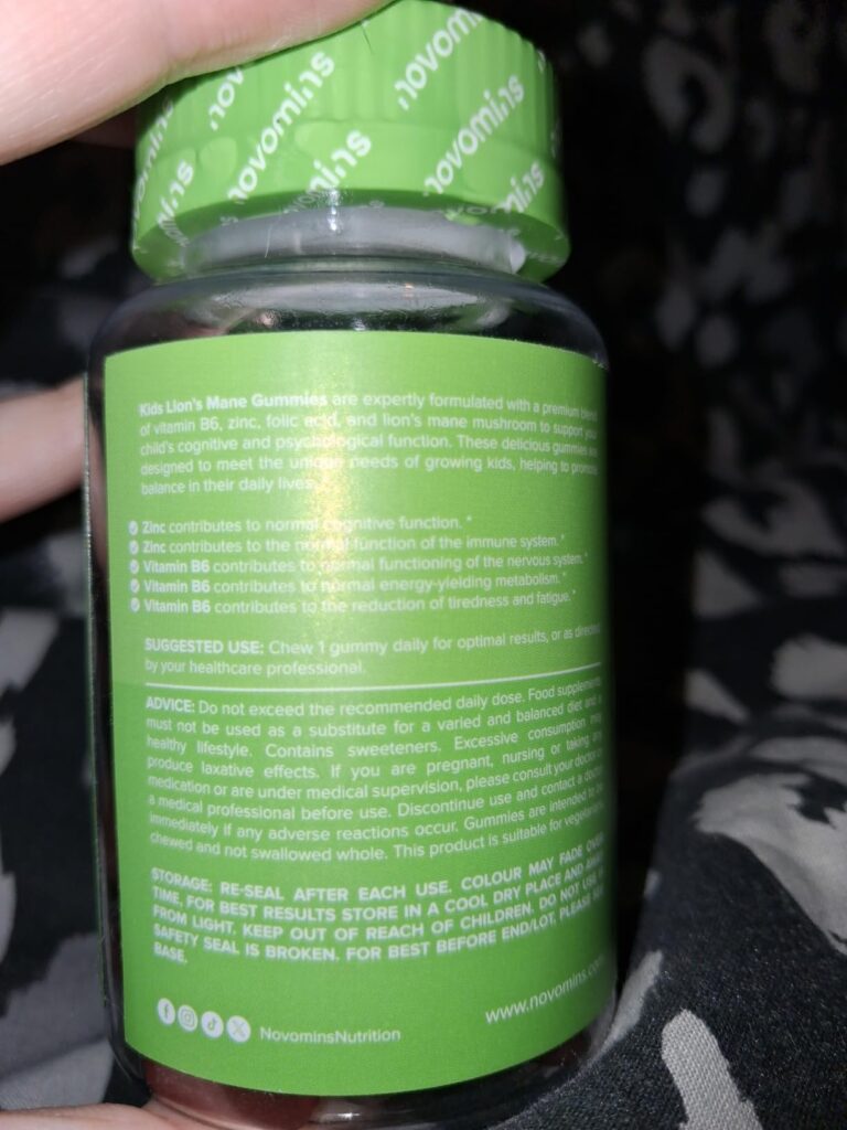 Bouteille de vitamines en gros plan, tenue dans une main, avec l'étiquette arrière et les instructions visibles