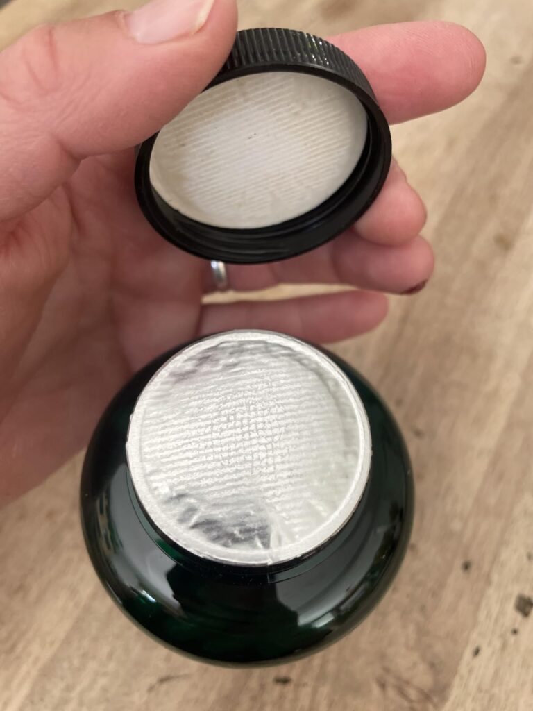 Bouteille de compléments alimentaires, vue du dessus, avec le couvercle ouvert montrant l'opercule de protection.