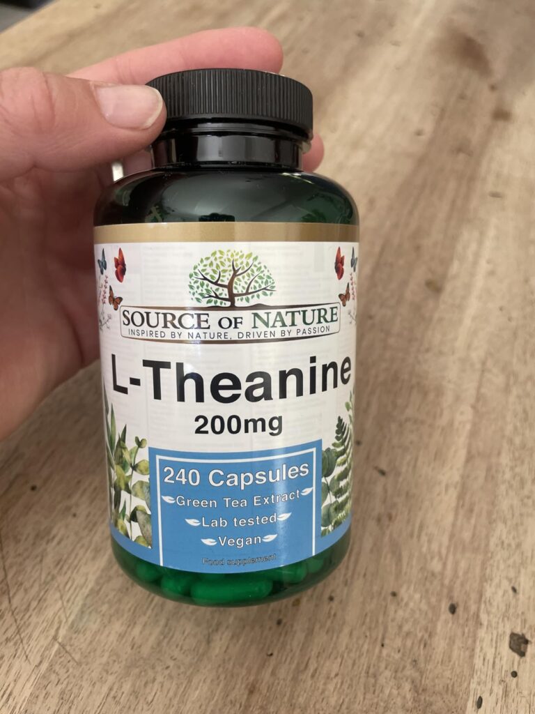 Bouteille de compléments alimentaires tenue dans une main, vue de face.