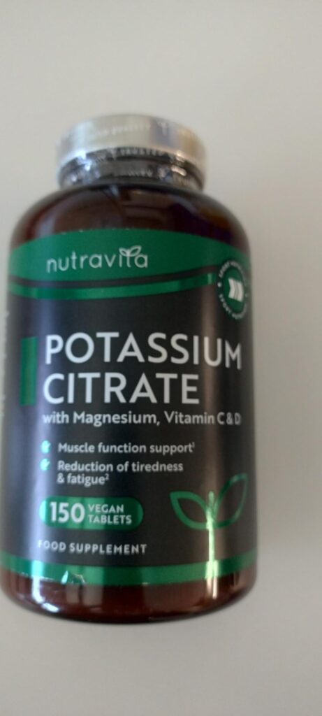 Flacon de compléments alimentaires Nutravita Potassium Citrate sur fond blanc, vue légèrement oblique.
