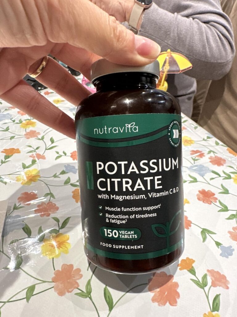 Flacon de compléments alimentaires Nutravita Potassium Citrate tenu par une main.