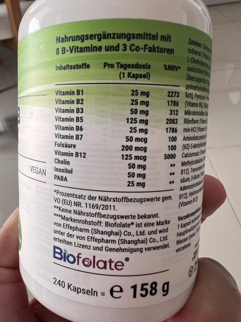 Flacon de compléments alimentaires, face arrière avec les valeurs nutritionnelles, tenu à la main.