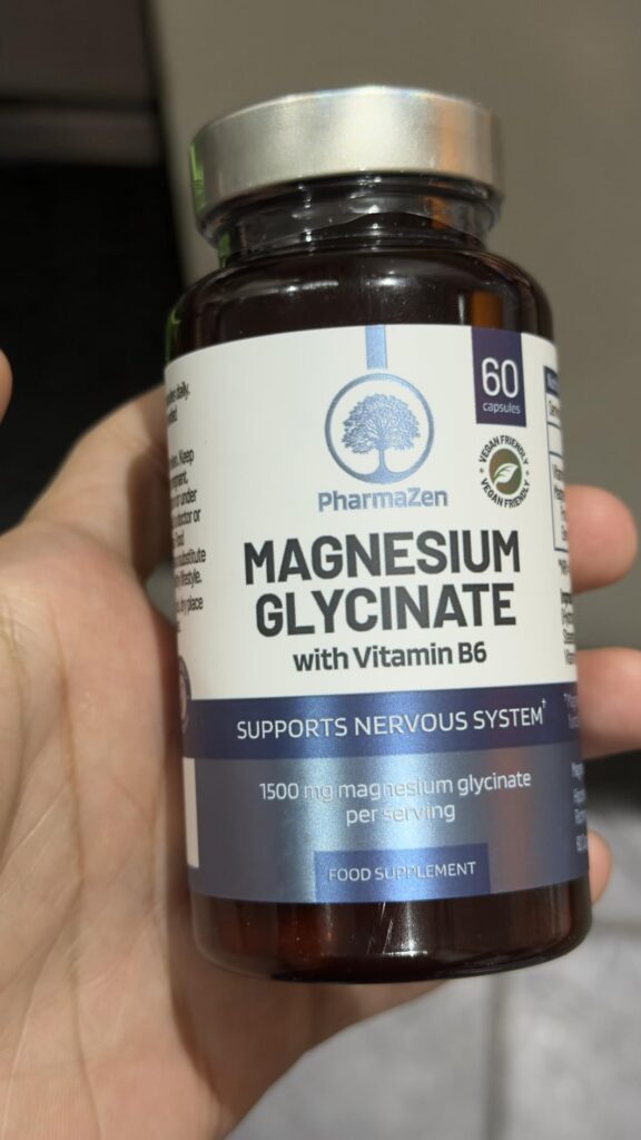 Bouteille de magnésium PharmaZen, tenue en main avec le couvercle argenté et l'étiquette bien visible. Le texte indique 60 ca...