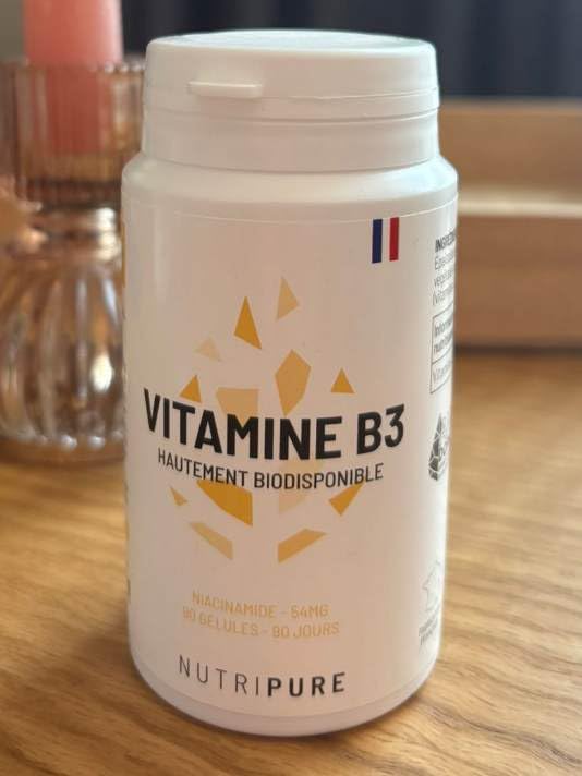 Flacon de Vitamine B3 sur fond neutre. Visuel pris de près.