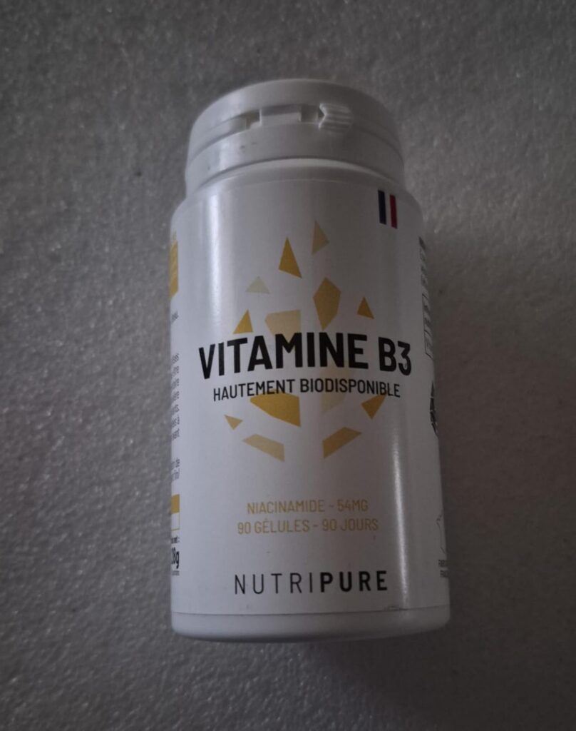 Flacon de Vitamine B3 sur fond neutre. Visuel pris de loin.