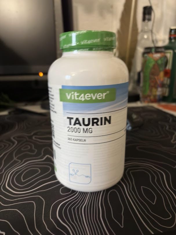 Bouteille de compléments alimentaires 'Taurin 2000 MG' de la marque Vit4ever, vue de face sur un bureau avec un écran d'ordin...