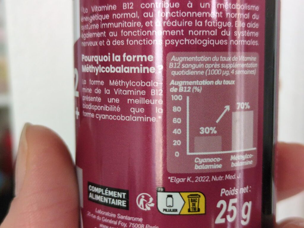 Partie arrière de l'étiquette du flacon de complément alimentaire Santarome Vitamine B12 tenue dans une main, montrant un gra...