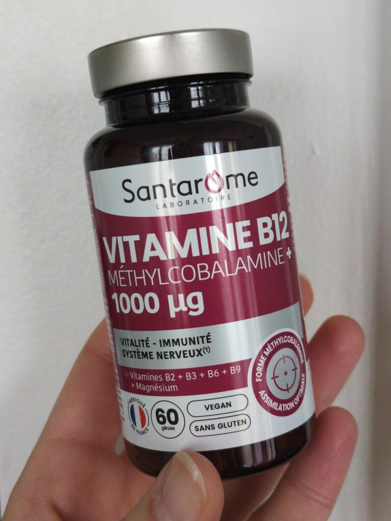 Flacon de complément alimentaire Santarome Vitamine B12 tenu dans une main, vue frontale légèrement en biais.