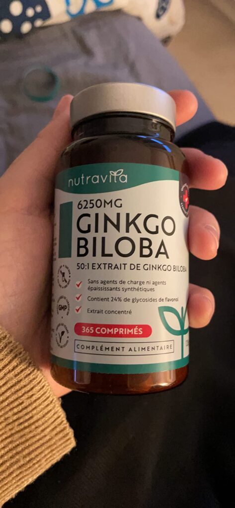 Un flacon de Ginkgo Biloba tenu dans une main, mettant l'accent sur l'étiquette.