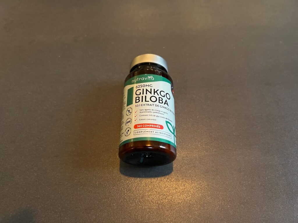 Un flacon de Ginkgo Biloba posé sur une surface grise unie.