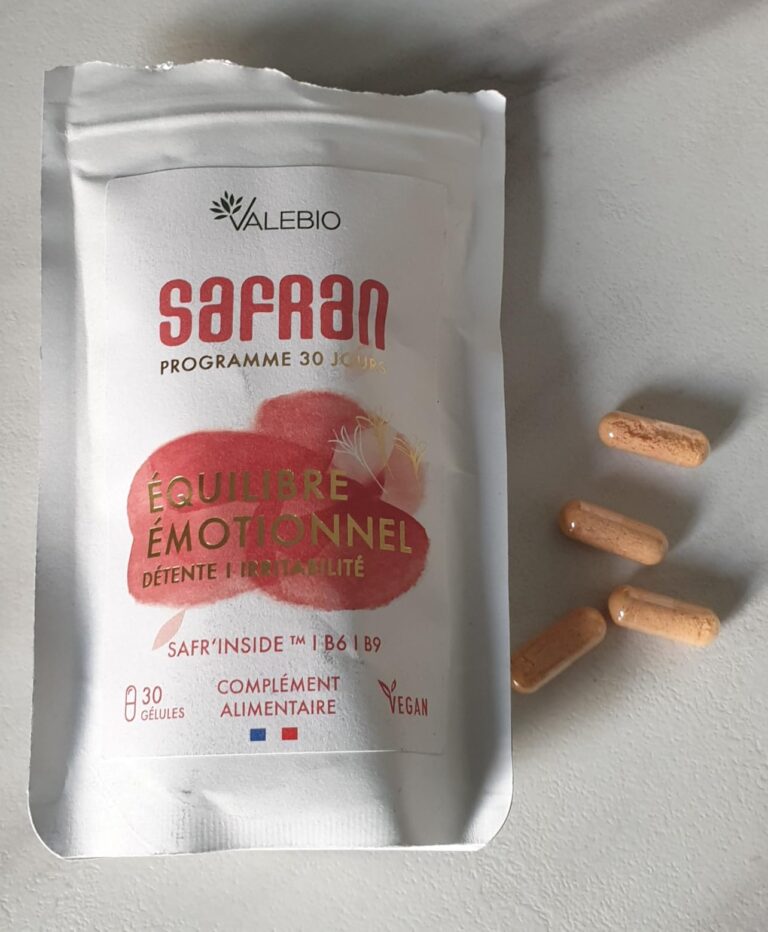 Sachet de compléments alimentaires au safran et quelques gélules posées à côté sur une surface blanche