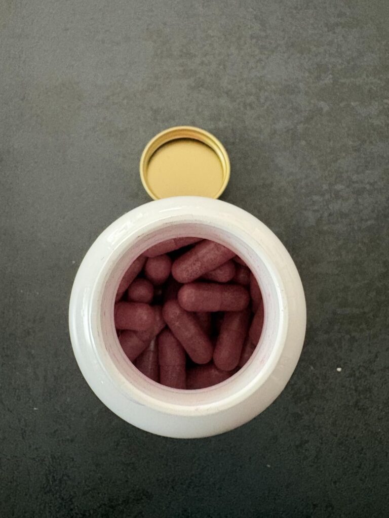 Vue de dessus de la bouteille ouverte, montrant les capsules à l'intérieur. Le bouchon est posé à côté.
