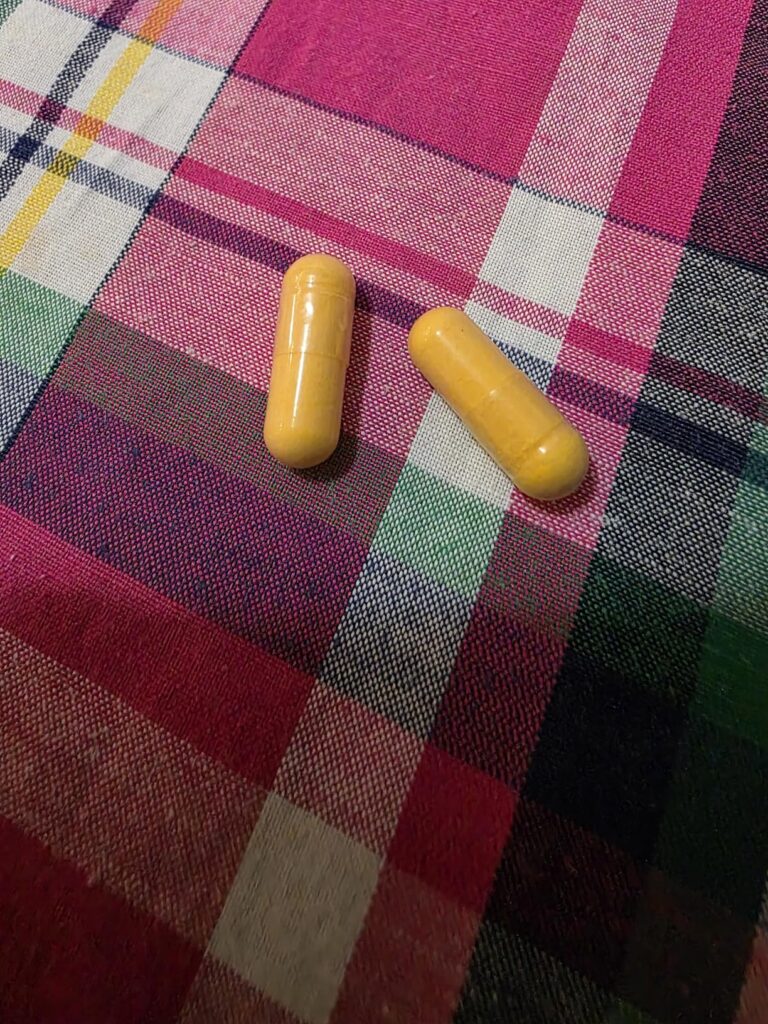 Deux capsules de couleur jaune-orange sur un tissu à carreaux roses et verts